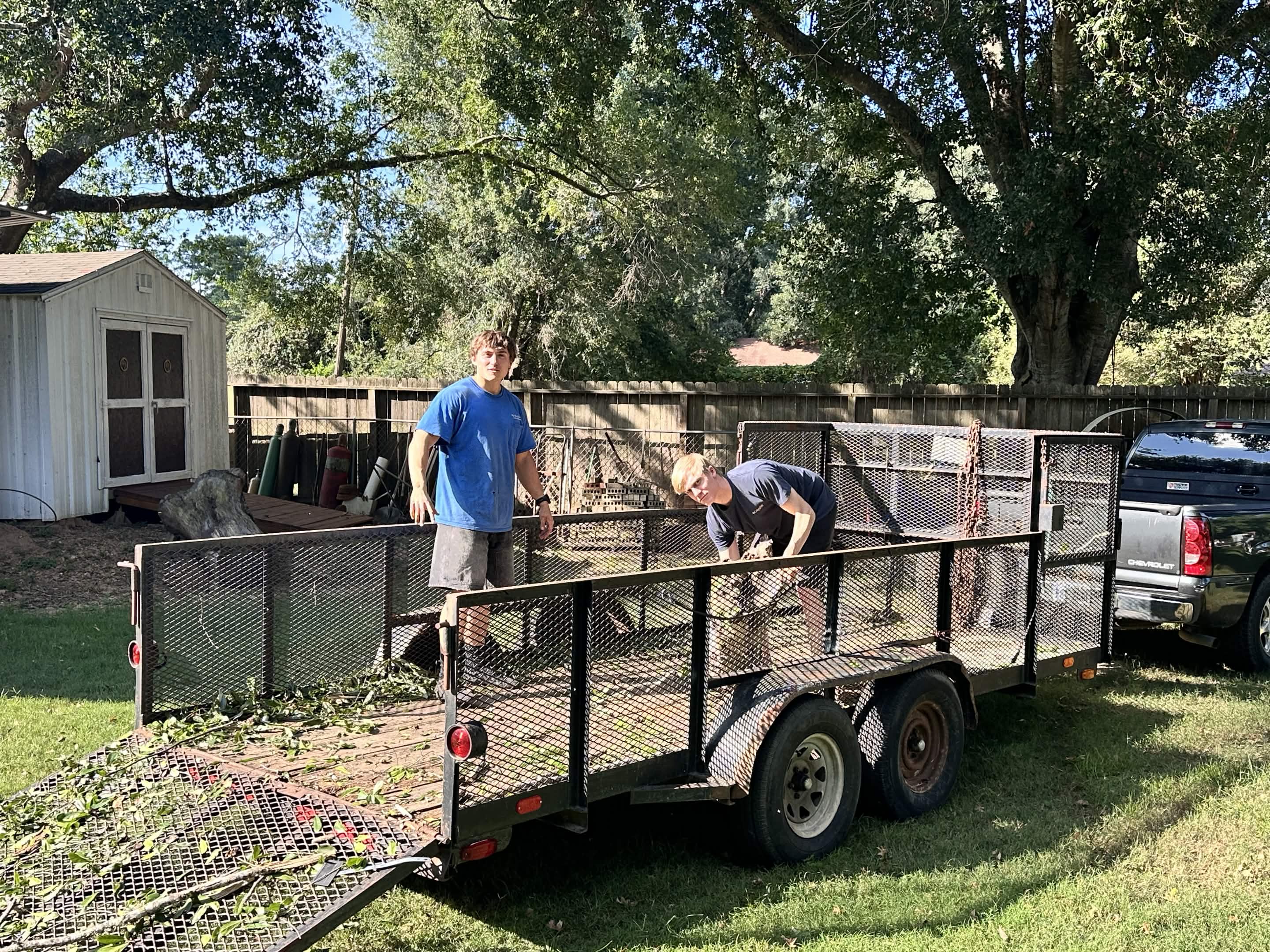 Philip and Jacob Swindle loading debris onto a work trailer